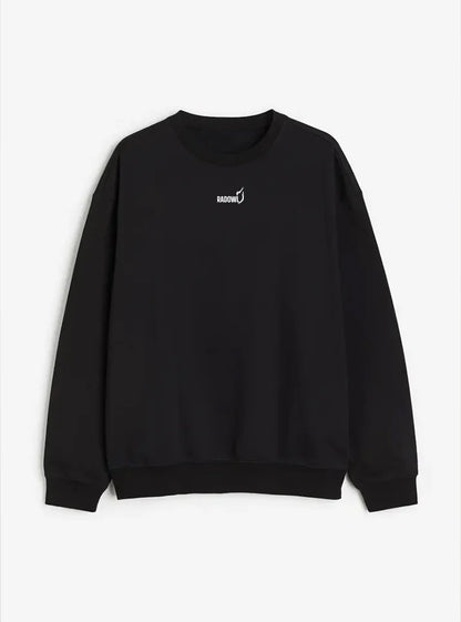 This images show Radowl Sweatshirt is lying on white background and this product name is "Grind Oversized Sweatshirt Black" it's black in colour and white colur Radowl logo and signature printed on it.